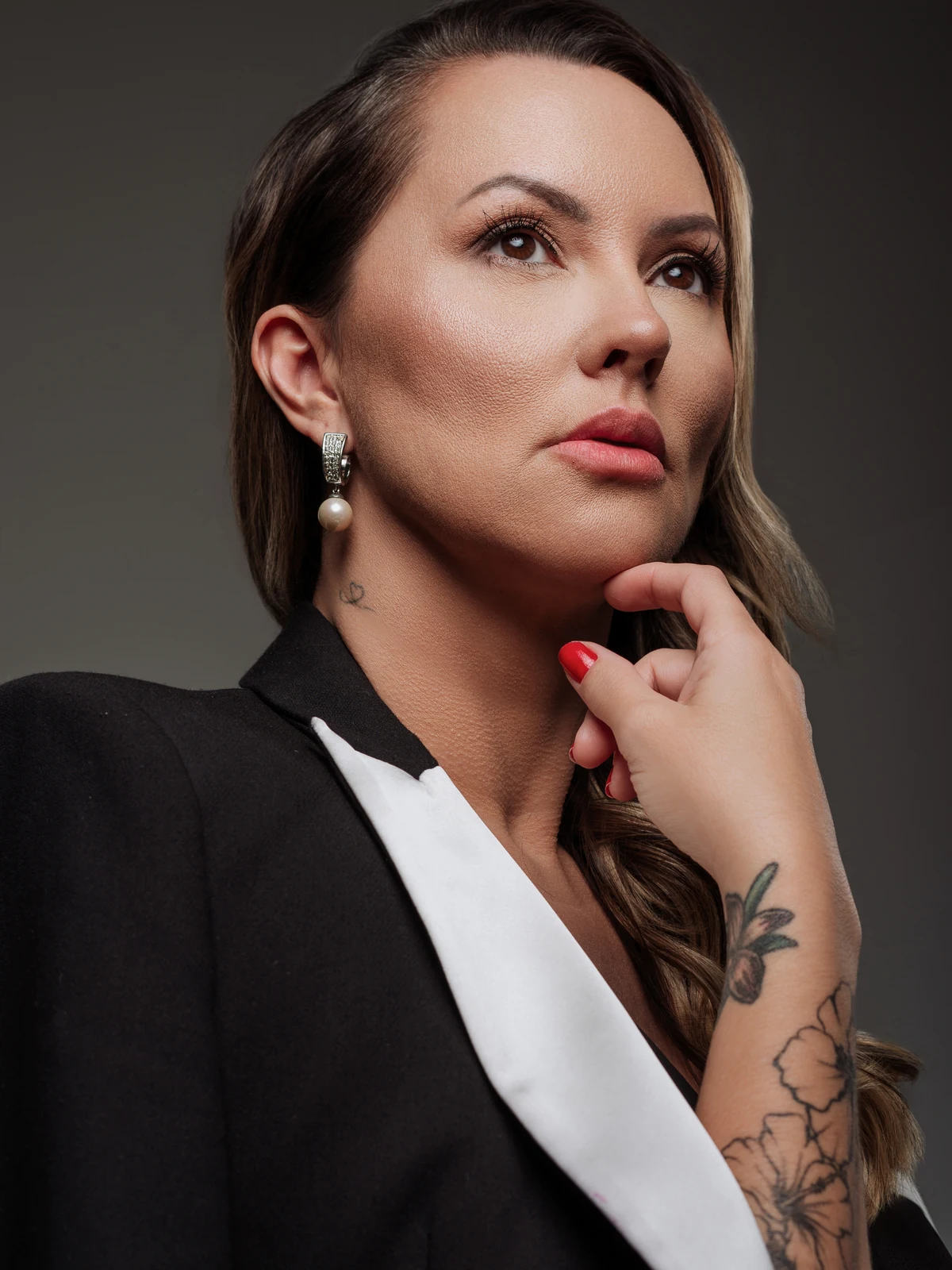 Dra. Joan Mason de blazer preto e camisa branca, mão apoiada no queixo